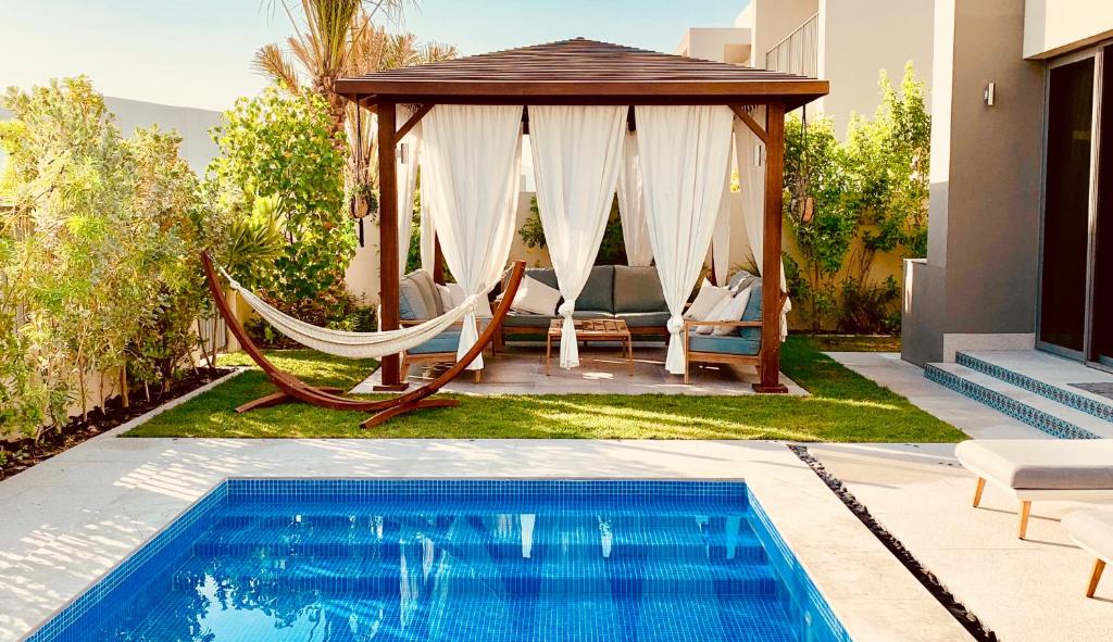 迪拜The Sunshine Villa的游泳池旁的吊床和凉亭