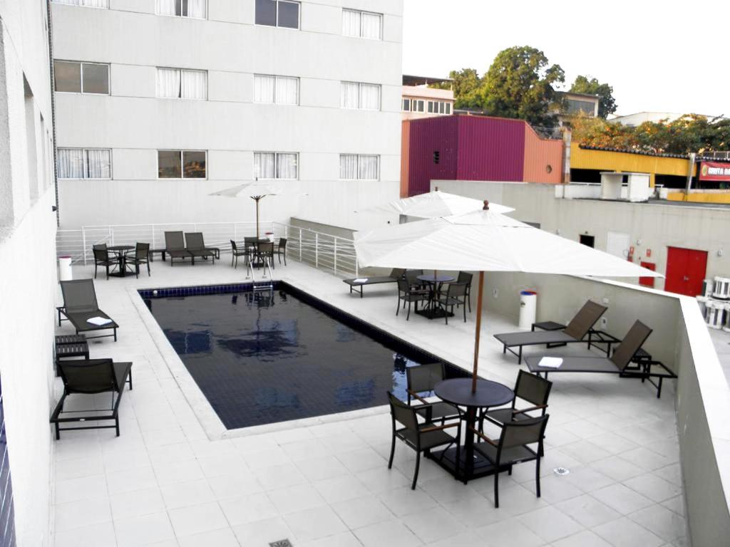 圣若昂迪梅里蒂Nobile Inn Dutra Rio De Janeiro的一座带桌椅的庭院和一座位于大楼内的游泳池