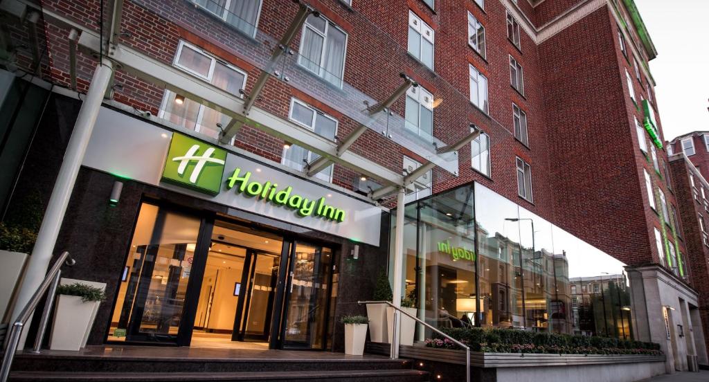 伦敦Holiday Inn London Kensington High St., an IHG Hotel的砖楼前的商店,上面有标志