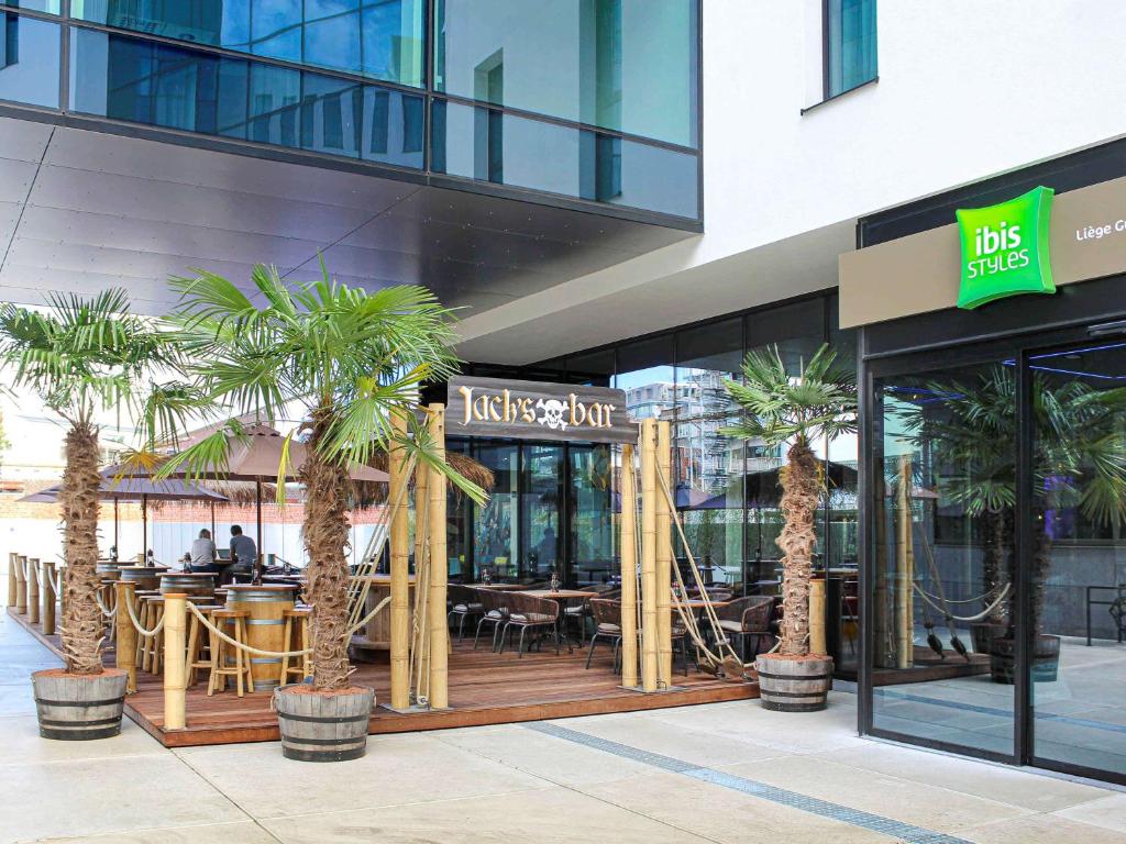 列日ibis Styles Liege Guillemins的一座楼前种有棕榈树的餐厅