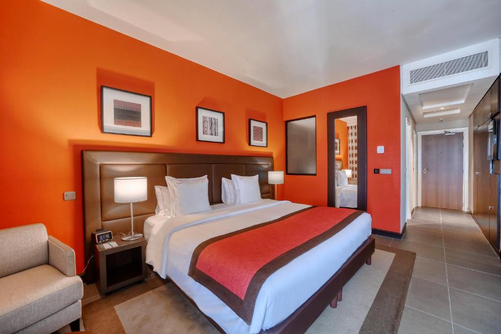 杜阿拉AKWA PALACE Douala的一间卧室配有一张带橙色墙壁的大床