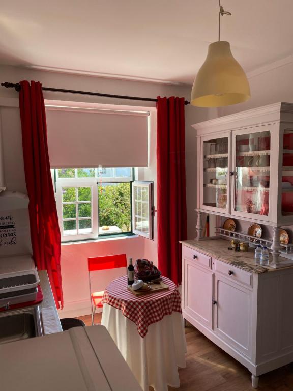 埃斯特雷莫斯Casa do Morgado do Casco的一间厨房,配有红色窗帘和桌子
