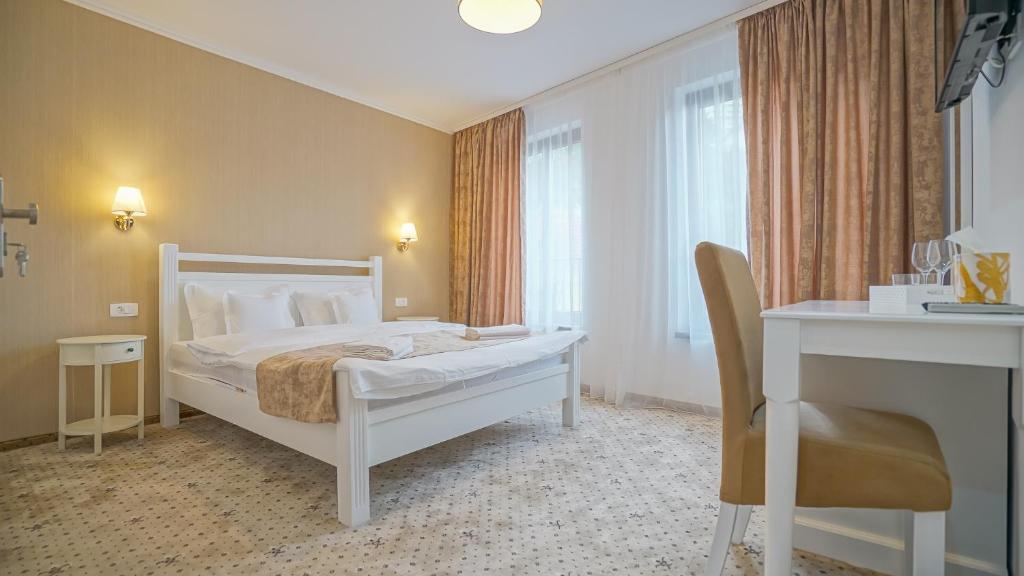 布拉索夫Monarch House的一间卧室配有一张床、一张桌子和一把椅子