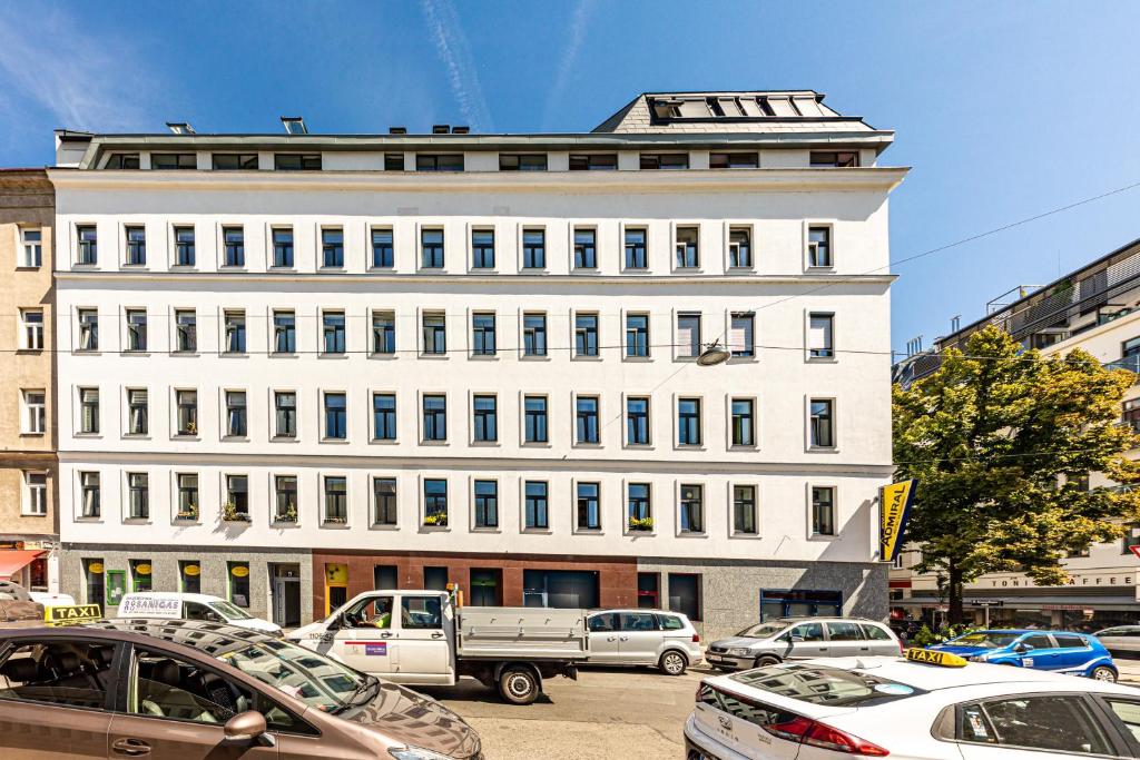 维也纳维也纳JR城市公寓的一座白色的大建筑,前面有汽车停放