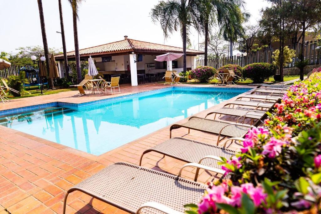 雅瓜里乌纳Hotel Residence Jaguary的一个带长椅和桌子的游泳池以及鲜花