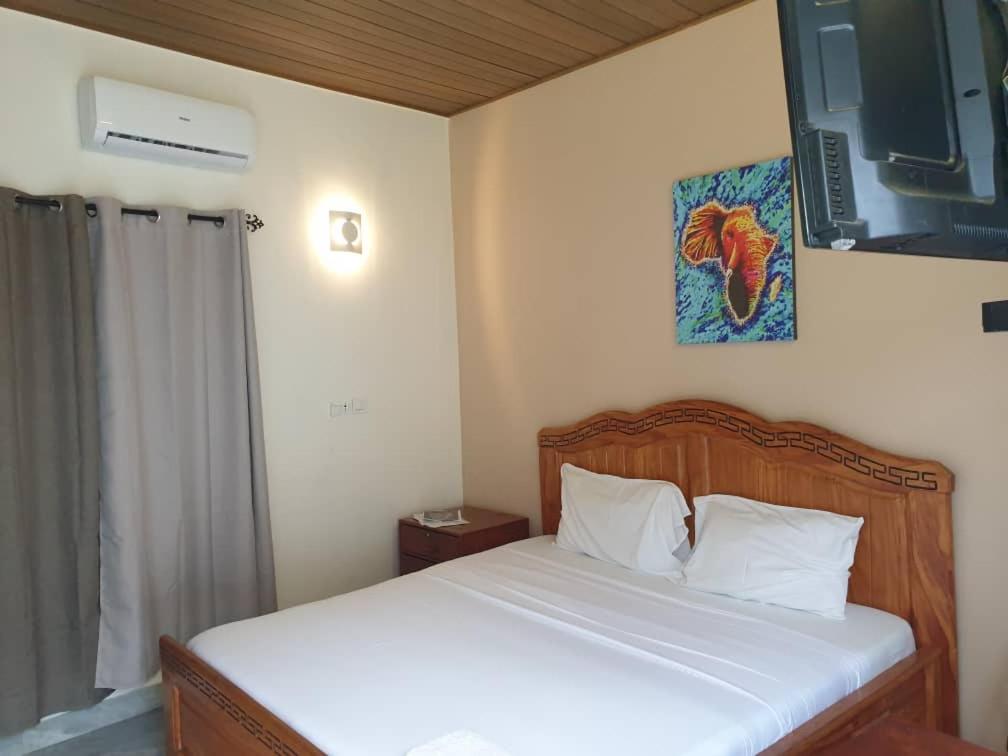 科托努Residence Ivoire Cotonou的卧室配有一张带白色床单的床,墙上挂着一幅画