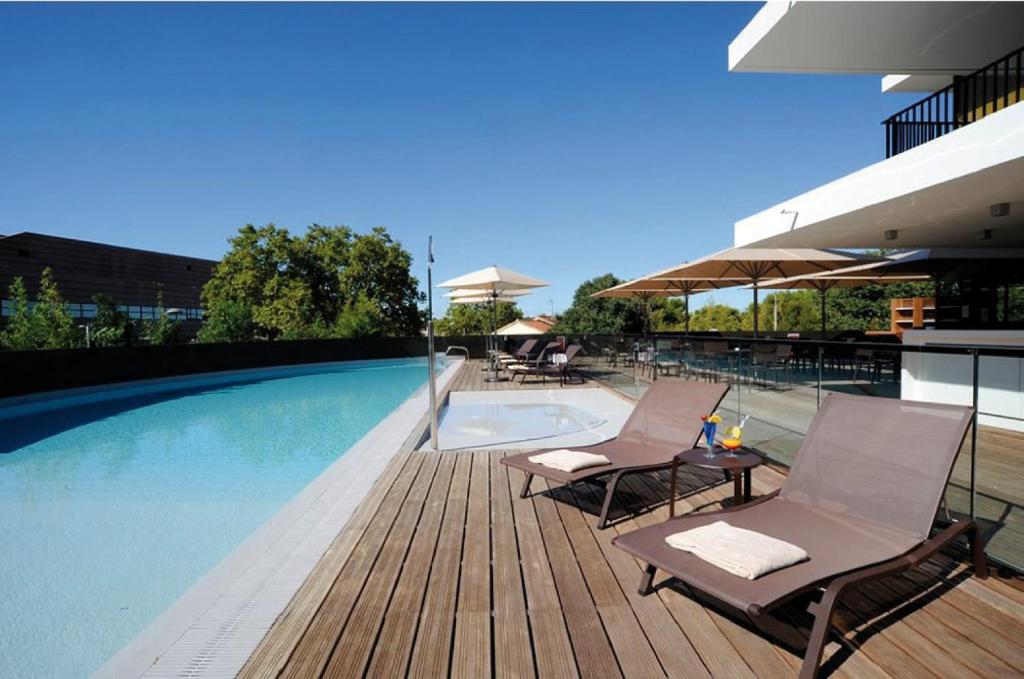 蒙彼利埃皇冠假日佩里尔峰库尔姆酒店的游泳池旁设有两把椅子和一张桌子