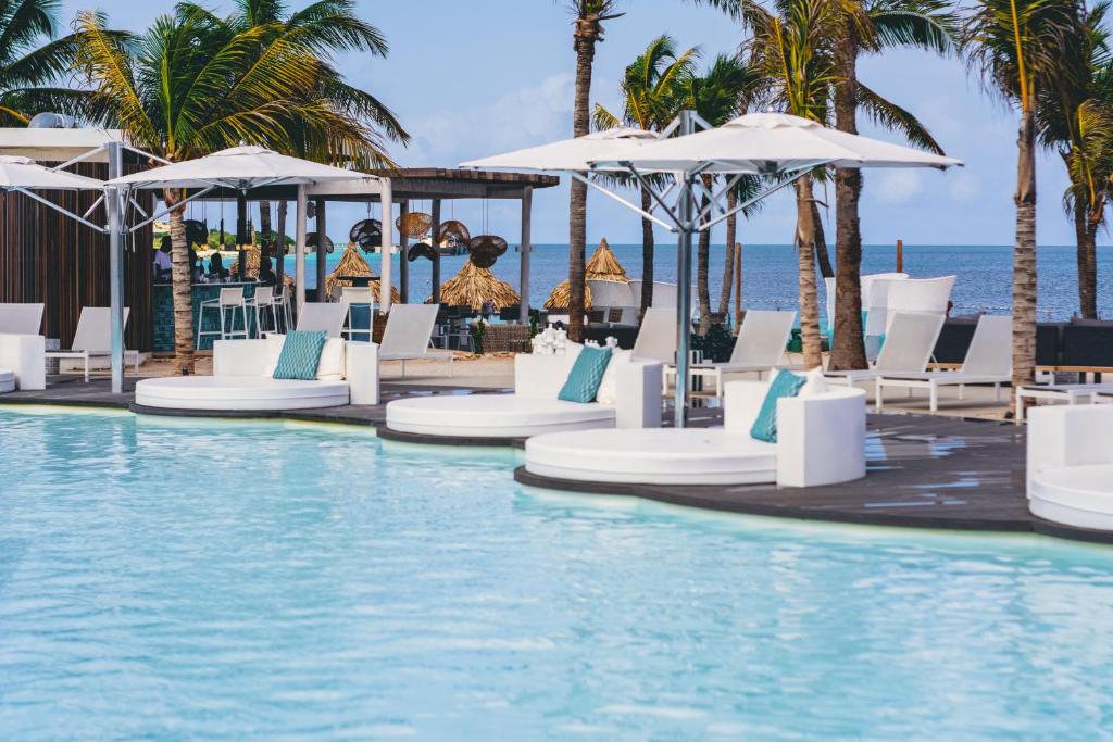 克拉伦代克Van der Valk Plaza Beach & Dive Resort Bonaire的毗邻大海的带椅子和遮阳伞的游泳池