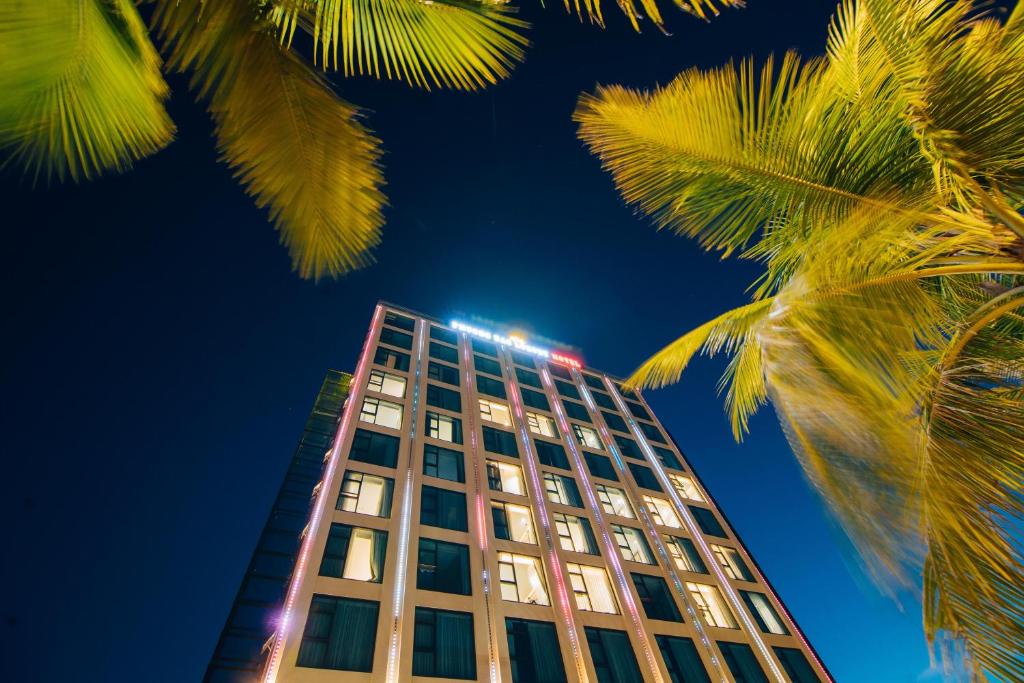 洞海Phương Bắc Luxury Hotel的一座高大的建筑,前面有棕榈树