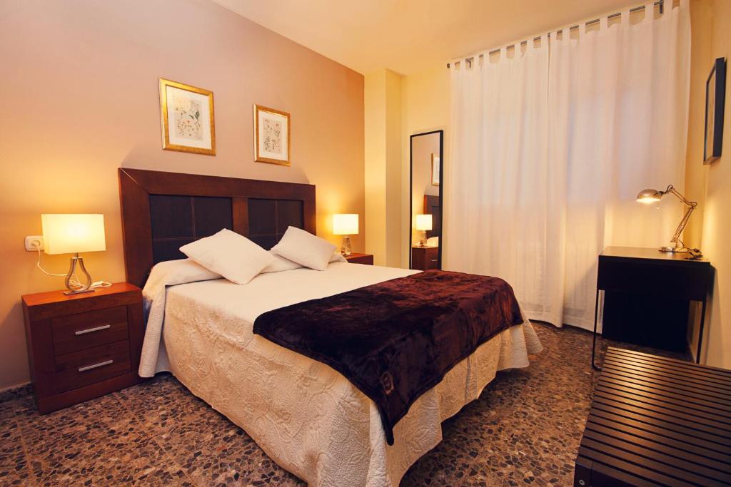 梅里达赛勒斯旅游公寓的一间卧室配有一张大床、两盏灯和一个窗户。
