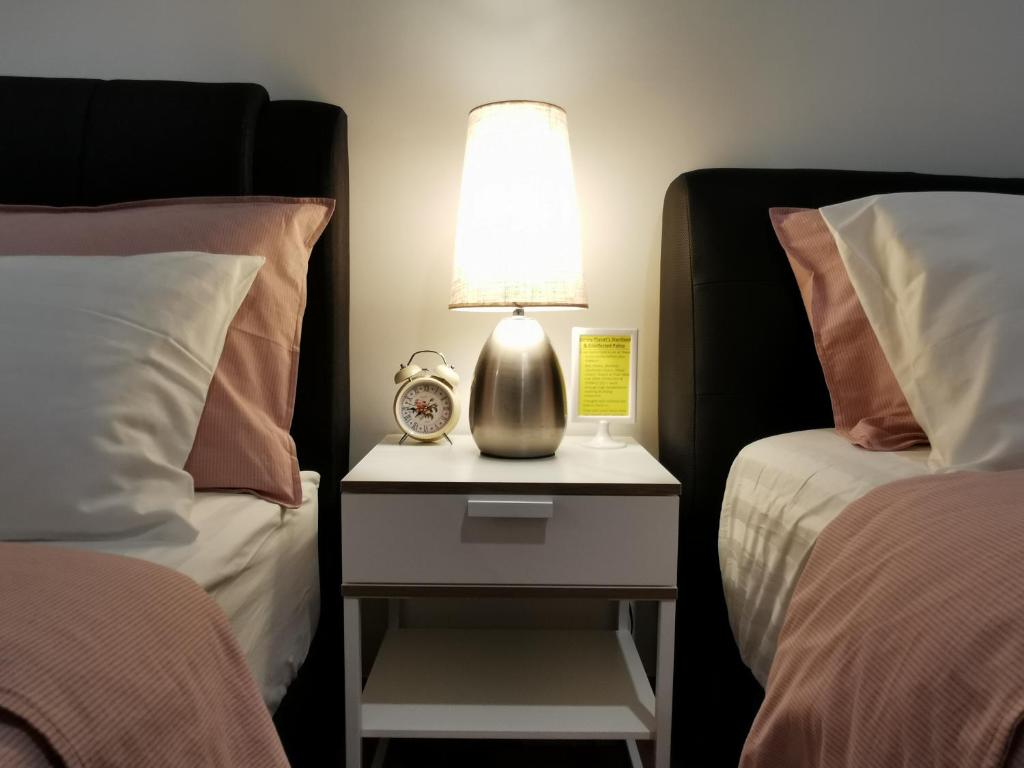 丹绒道光Landmark Lovely Coast View King Suite#500mbpsWifi#Netflix的两床之间的床头柜上的一盏灯