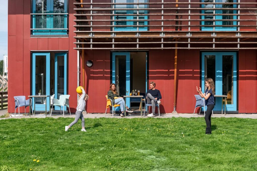 登堡Stayokay Hostel Texel的一群人走在一座建筑前面的草地上