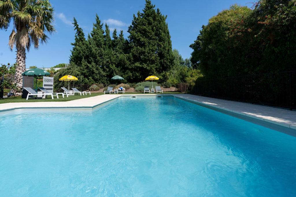 阿维尼翁阿维尼翁南部卡联达尔布里特酒店的一个带椅子和遮阳伞的大型蓝色游泳池