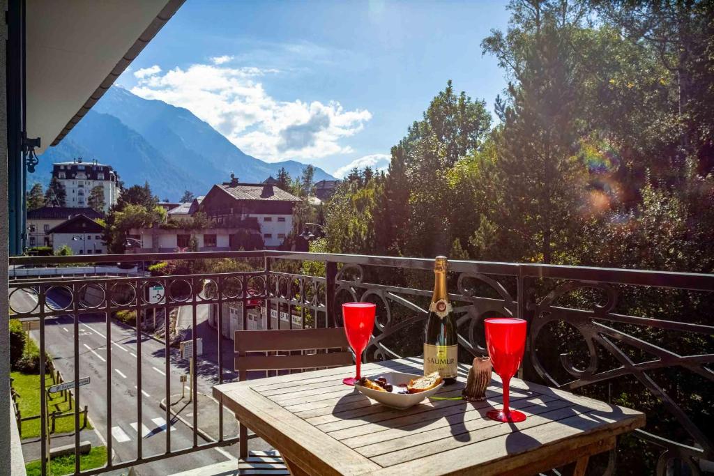 夏蒙尼-勃朗峰Le Paradis 15 Apartment - Chamonix All Year的阳台上的木桌和两杯酒杯