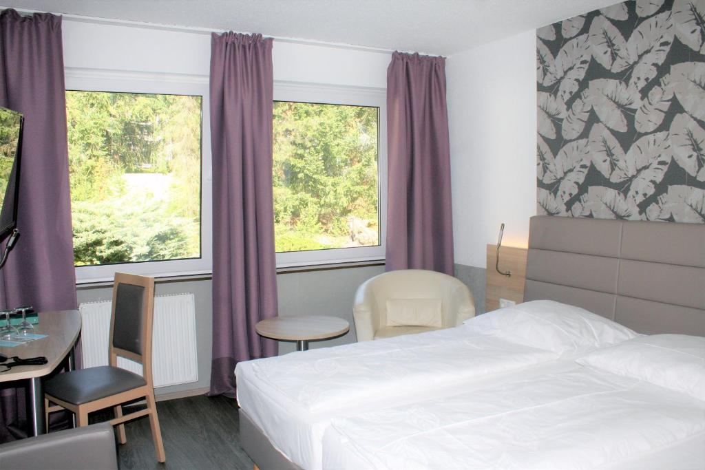 纽伦堡呃林斯特艮酒店的酒店客房设有一张床、一张桌子和两个窗户。