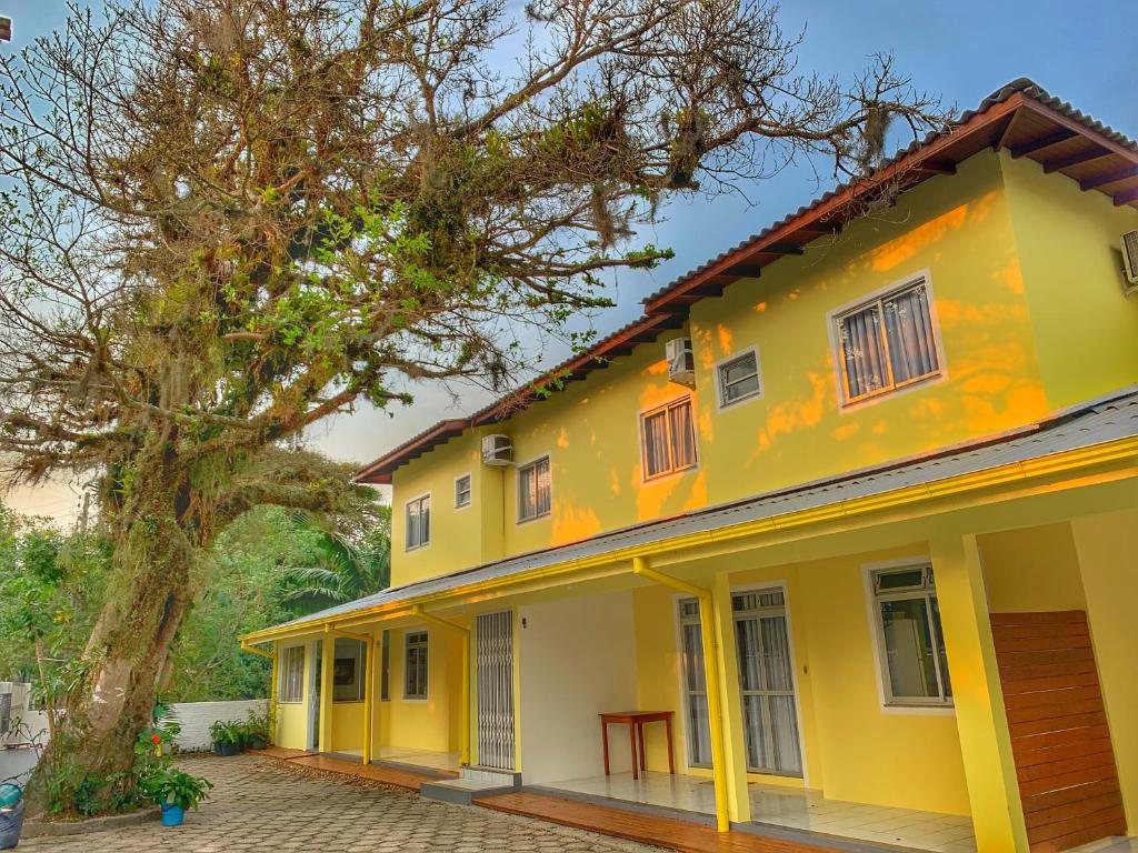 瓜尔达恩巴Pousada Figueira的旁边一棵树的黄色房子