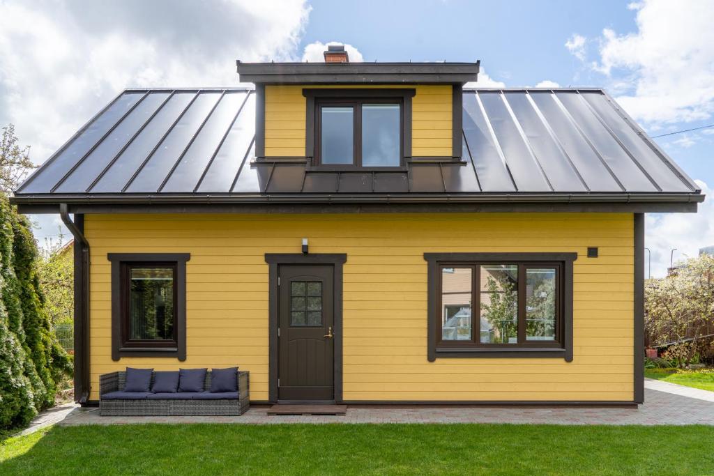 库雷萨雷Cosy Family Guesthouse with Sauna and Garden的黑色屋顶的黄色房子