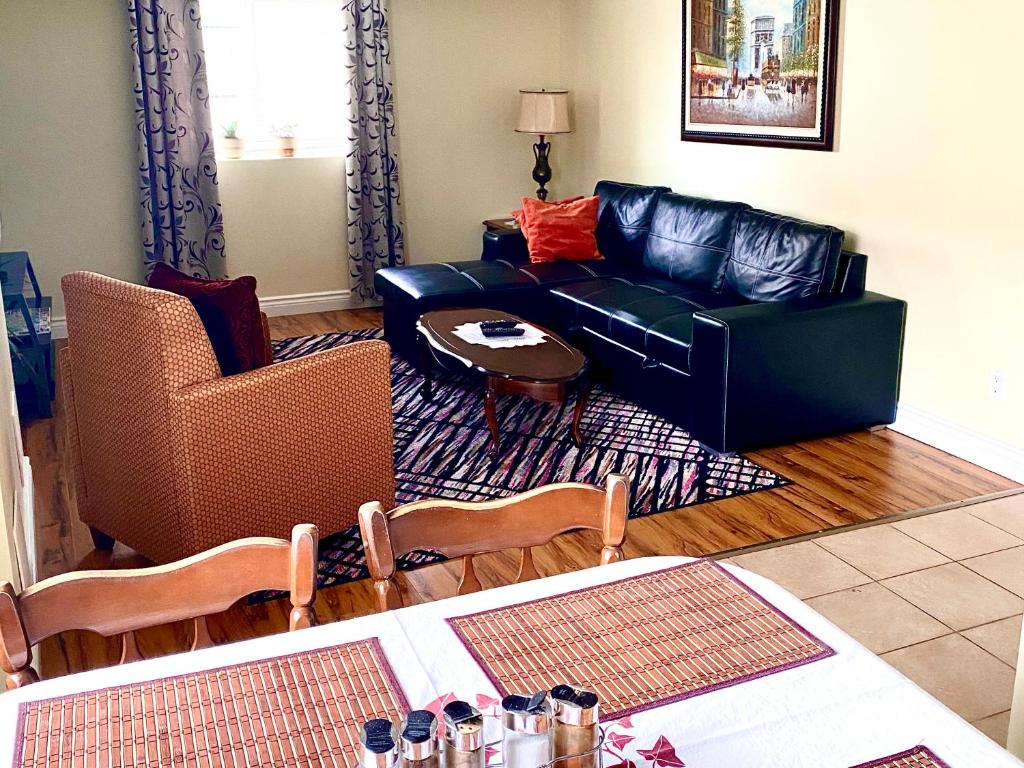 尼亚加拉瀑布Elgin Suite的客厅配有黑色真皮沙发和椅子