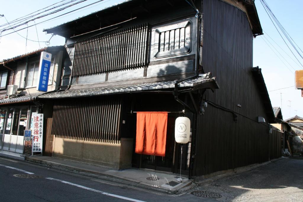 京都Guesthouse KYOTO COMPASS的一座黑色的建筑,门口挂着一条橙色毛巾