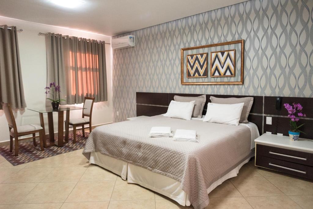 奥兰布拉Holambra Garden Hotel的一间带大床的卧室和一间餐厅