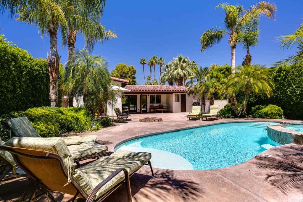 棕榈泉Poolside Terrace Permit# 1786的一个带椅子的游泳池以及一座棕榈树房子