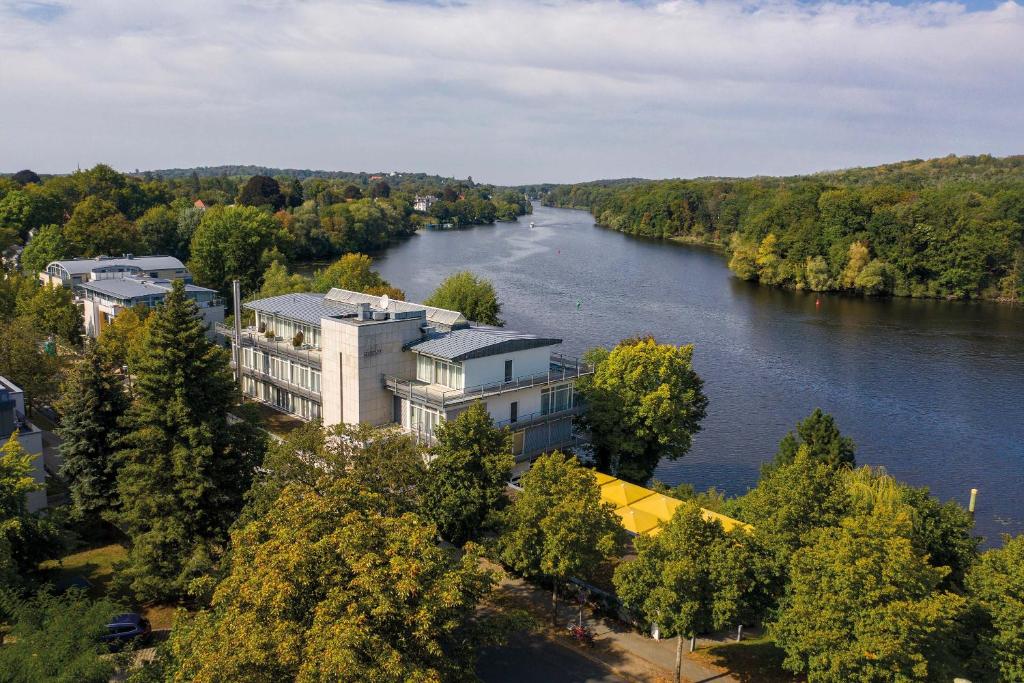波茨坦Seminaris Hotel Potsdam Griebnitzsee的享有河流美景,拥有建筑和树木