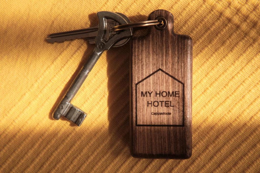 格雷梅My Home Cappadocia Stone House的一张木制房子钥匙,上面有家庭旅馆标签