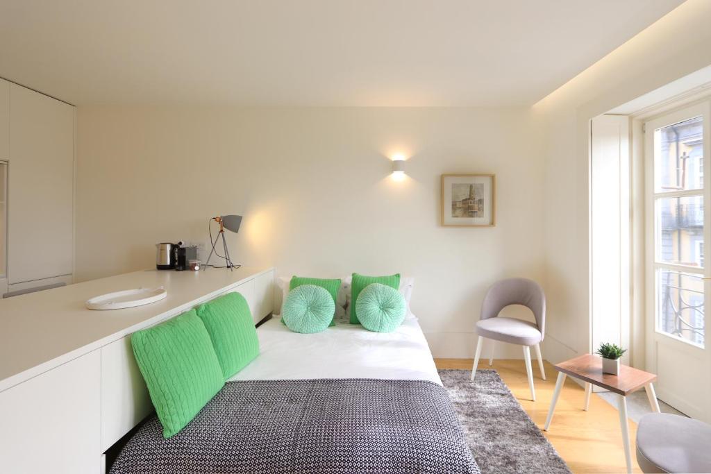 波尔图HM - Historical Studio Taipas 2D的客房配有带绿色枕头的床铺和柜台。