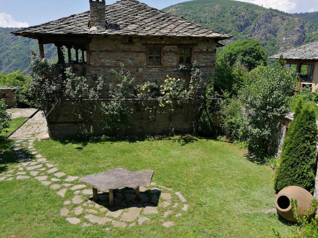 科瓦切维卡Къща за гости Кануш войвода的一座古老的石头房子,在院子里设有石凳