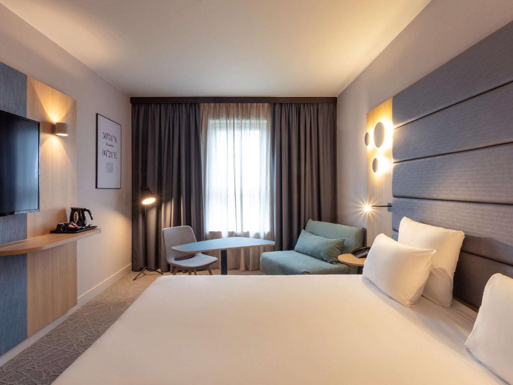 布鲁塞尔诺富特布鲁塞尔迷笛中心酒店的配有床、椅子和桌子的酒店客房