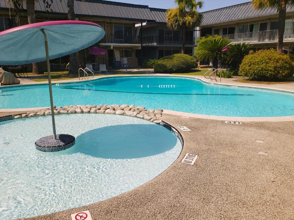 圣安东尼奥Extended Stay SA的一座带遮阳伞的游泳池位于大楼旁