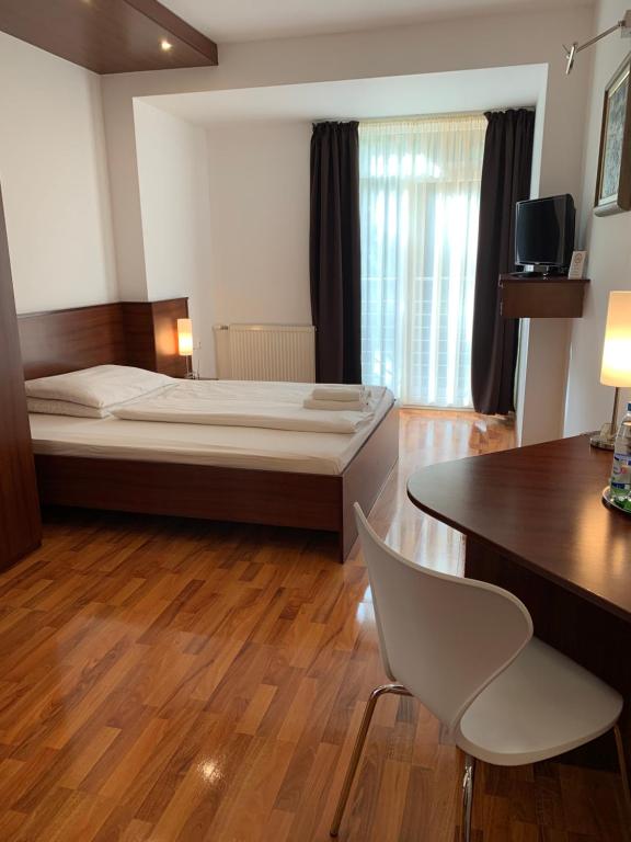 塞尼察Hotel Arli的卧室配有1张床、1张桌子和1把椅子