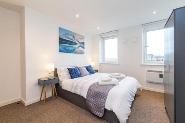 泰恩河畔纽卡斯尔Newcastle City Centre Apartment Ideal for Holiday, Contractors, Quarantining的一间卧室设有一张大床和两个窗户。