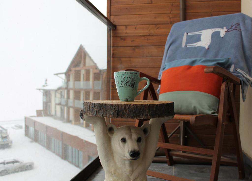 古多里Love Journey Gudauri的一只狗站在桌子下,拿着杯子站在桌子上