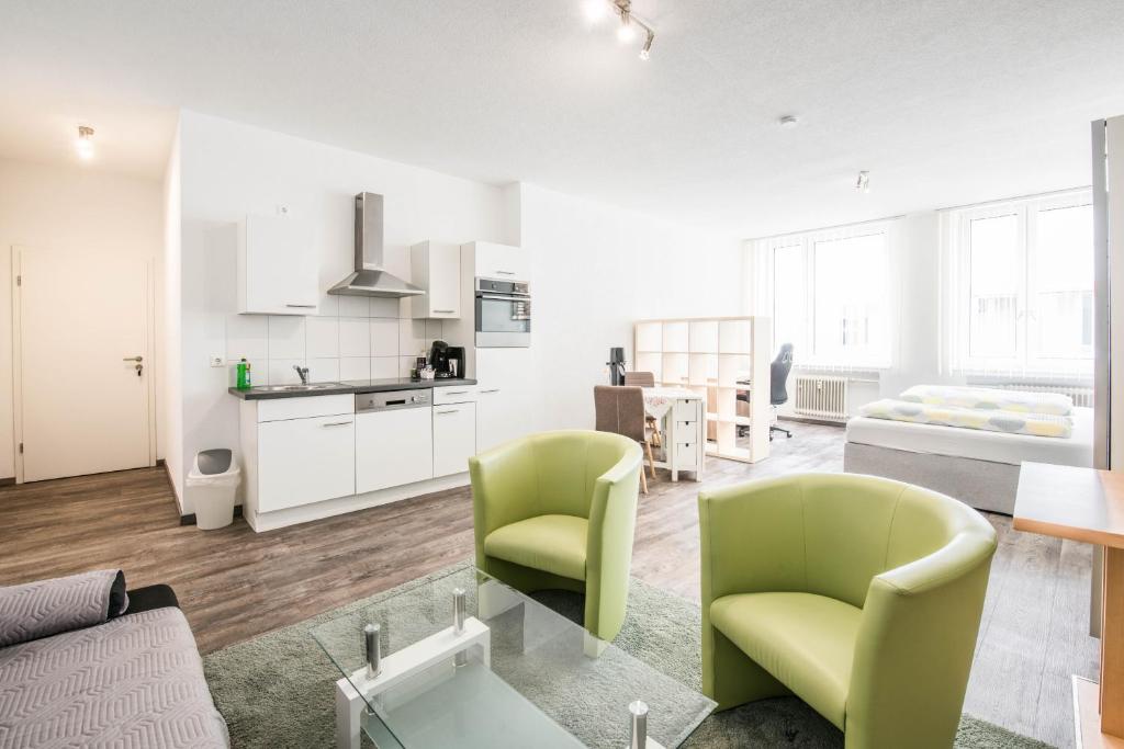 阿伦Apartmenthaus Aalen的一间带绿色椅子的客厅和厨房