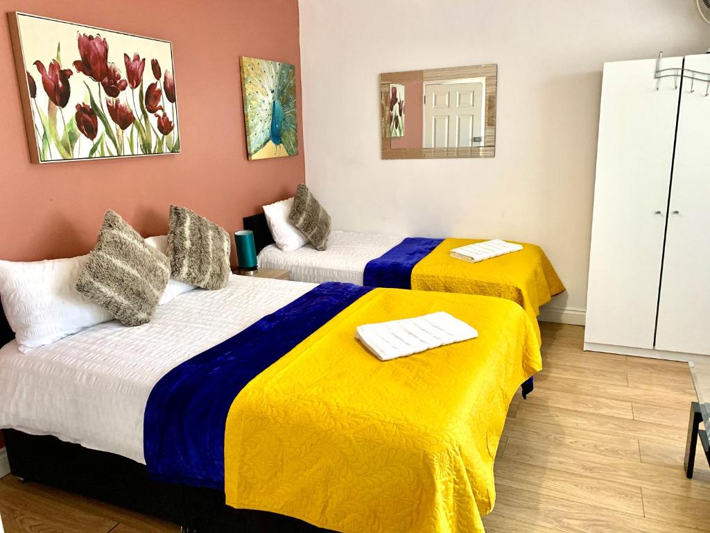 依尔福London Luxury Ensuite Apartment的配有两张黄色和蓝色床单的床铺
