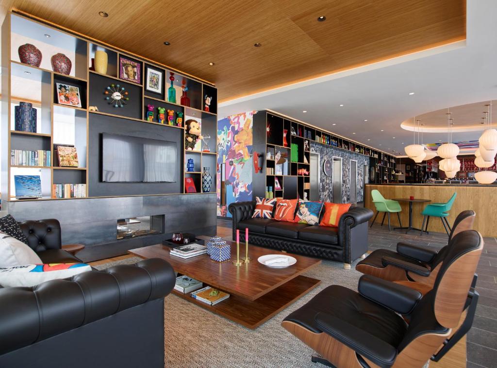 伦敦伦敦肖尔迪奇世民酒店的客厅配有黑色皮革家具和电视