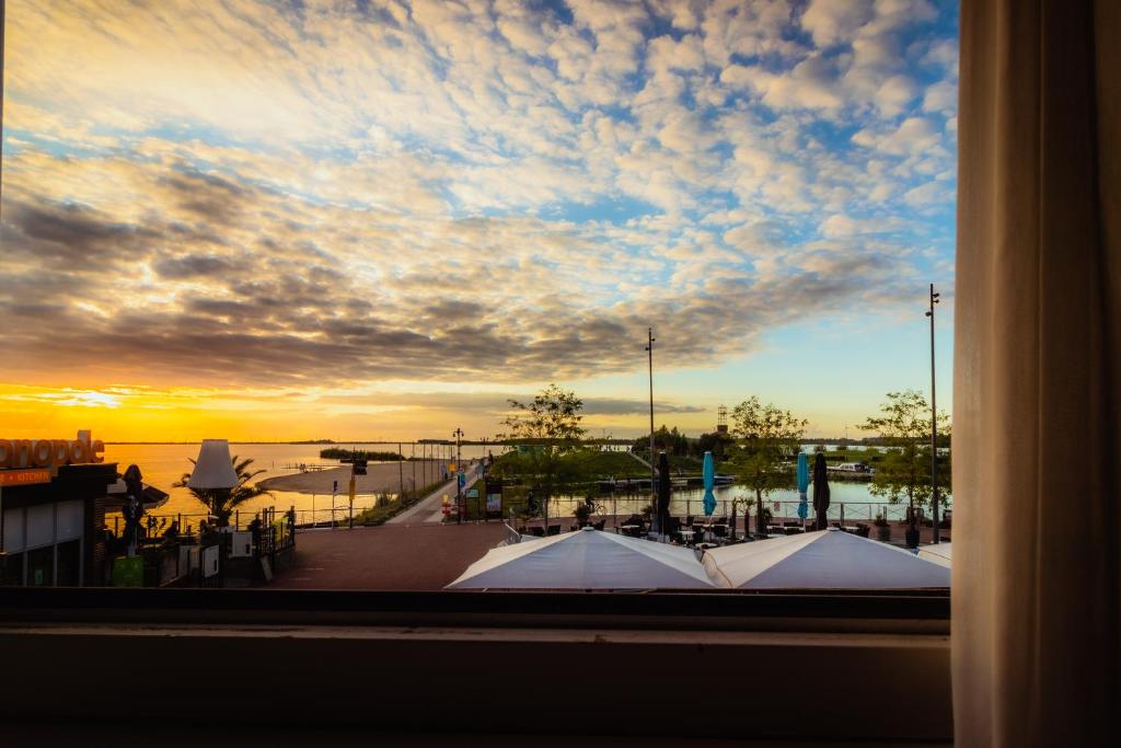 哈尔德韦克Hotel Bella Ciao的从日落时分的码头窗口欣赏美景