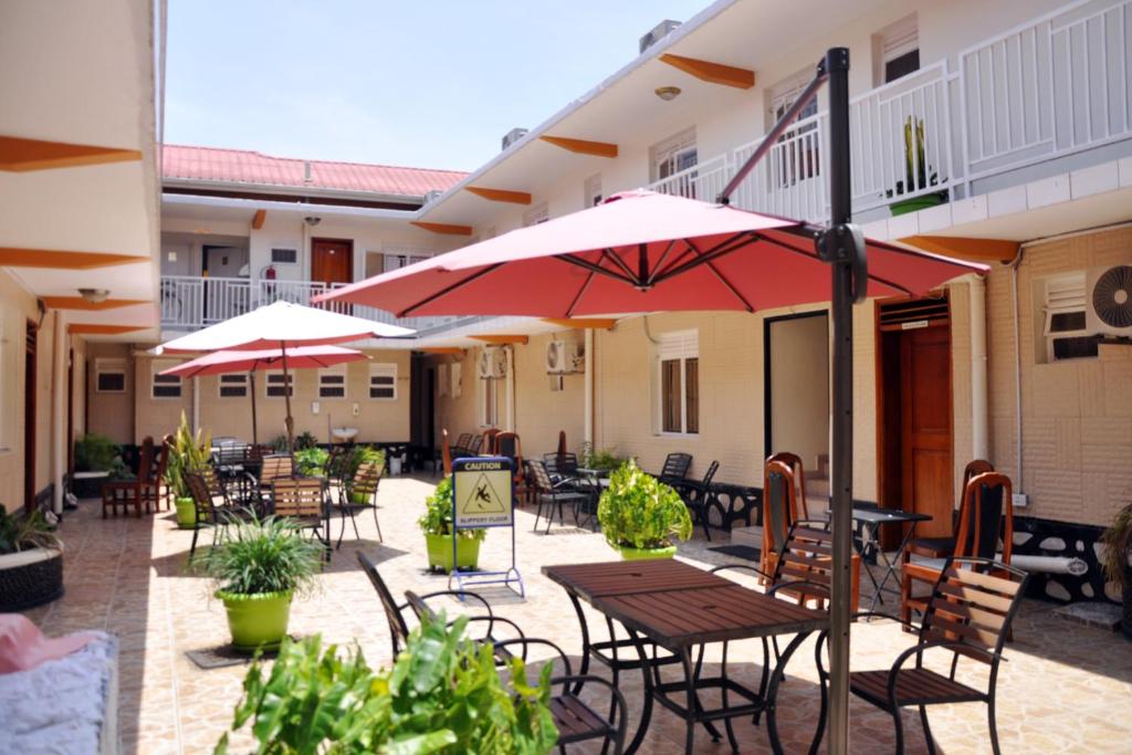 卡塞斯Sandton Hotel Kasese的一个带桌椅和遮阳伞的户外庭院。
