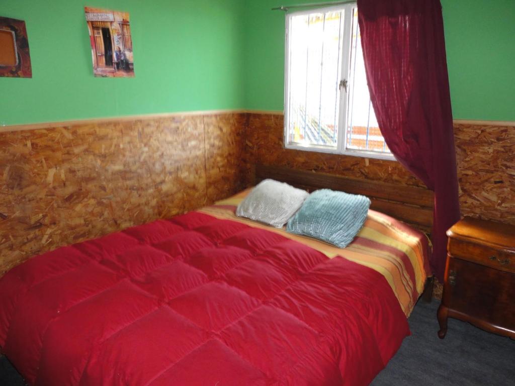 瓦尔帕莱索阿曼多旅馆 的一间卧室设有红色的床和窗户。
