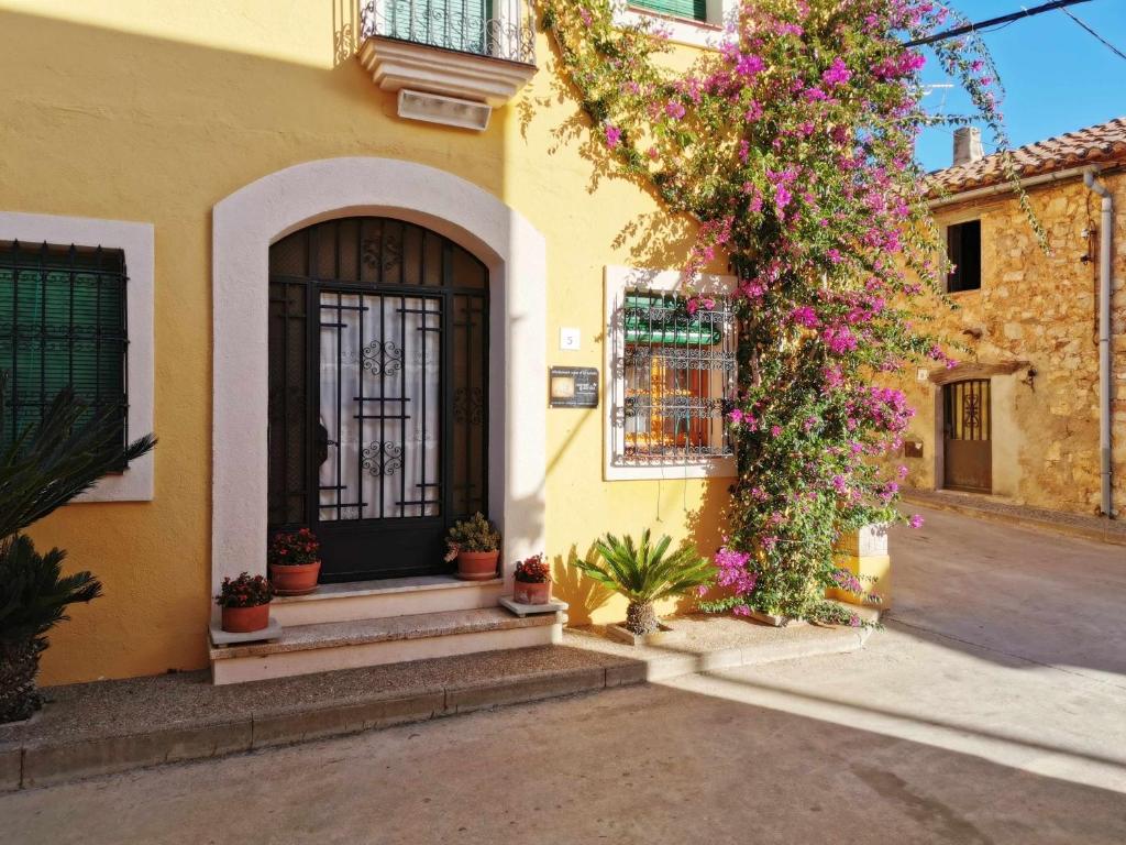 La GuardiolaJoanet Guarda turismo familiar en plena naturaleza的黄色的建筑,有黑色的门和鲜花