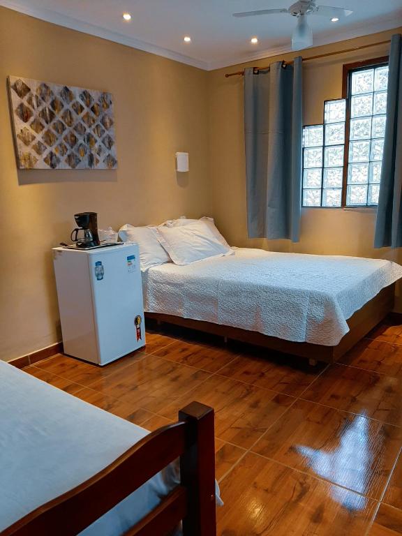 阿拉亚尔-杜卡布Suites Oliveira的一间卧室设有两张床和两个窗户。