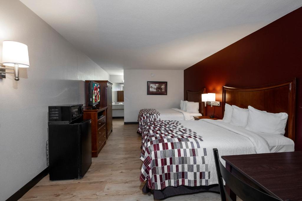 多森Red Roof Inn Dothan的酒店客房设有两张床和一张桌子。