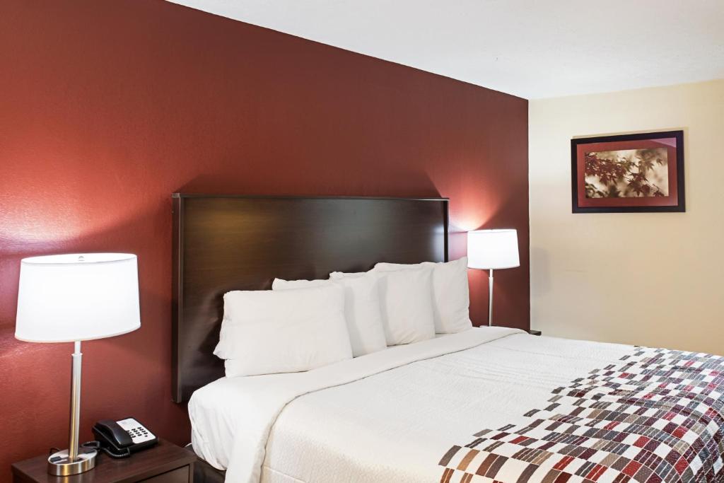 印第安纳波利斯Red Roof Inn Indianapolis East的酒店客房设有一张大床和两盏灯
