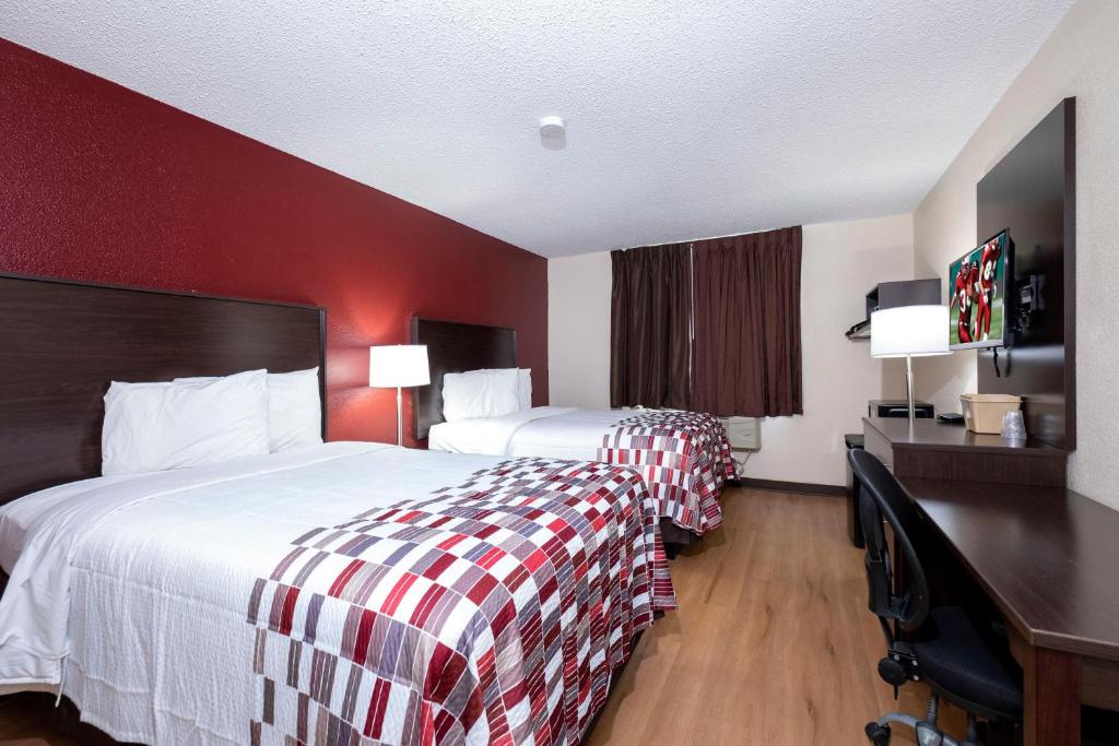 朴次茅斯Red Roof Inn Norfolk - Portsmouth的酒店客房设有两张床和红色的墙壁。