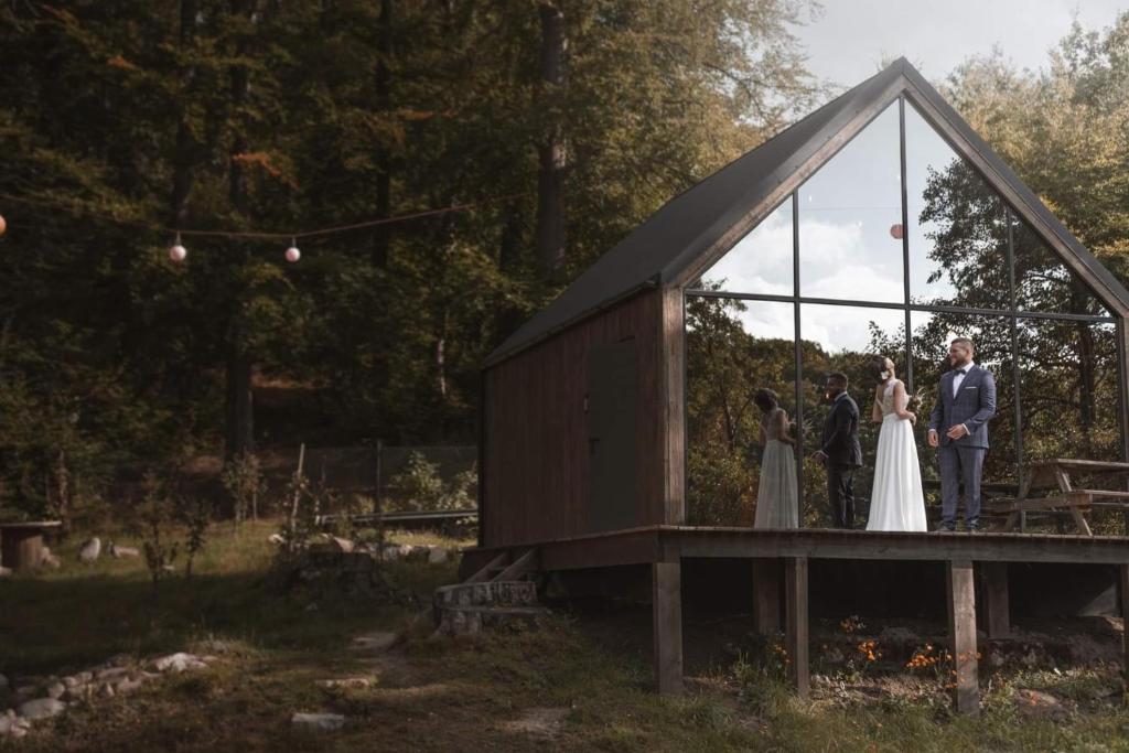 普日维兹Szklana Stodoła的站在玻璃房子里的一位新娘和新郎