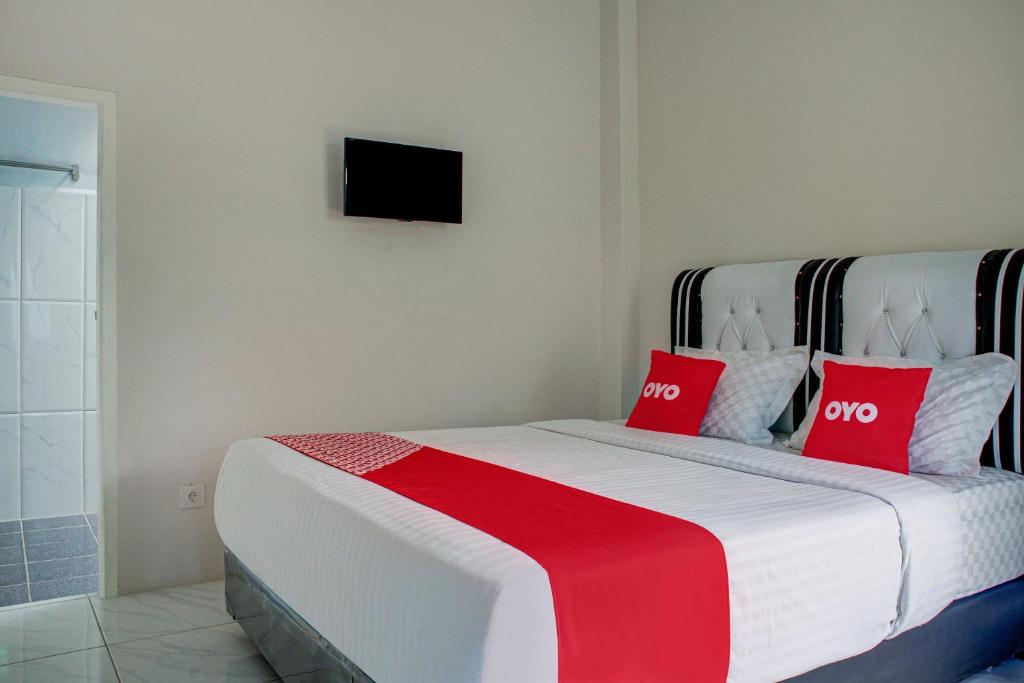 巴东OYO 3266 Alifah Residence Syariah的一间卧室配有一张带两个红色枕头的床