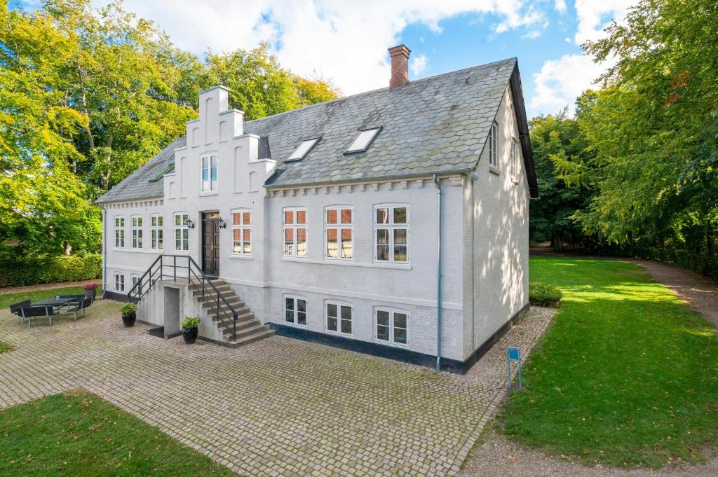 欧登塞Kragsbjerggaard的一座大型白色房子,在院子里设有楼梯