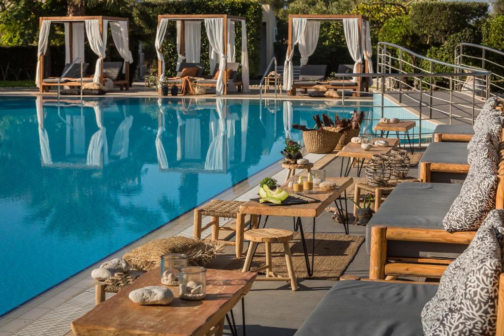 斯沃伦塔阿维托斯度假酒店的酒店旁的游泳池配有桌椅