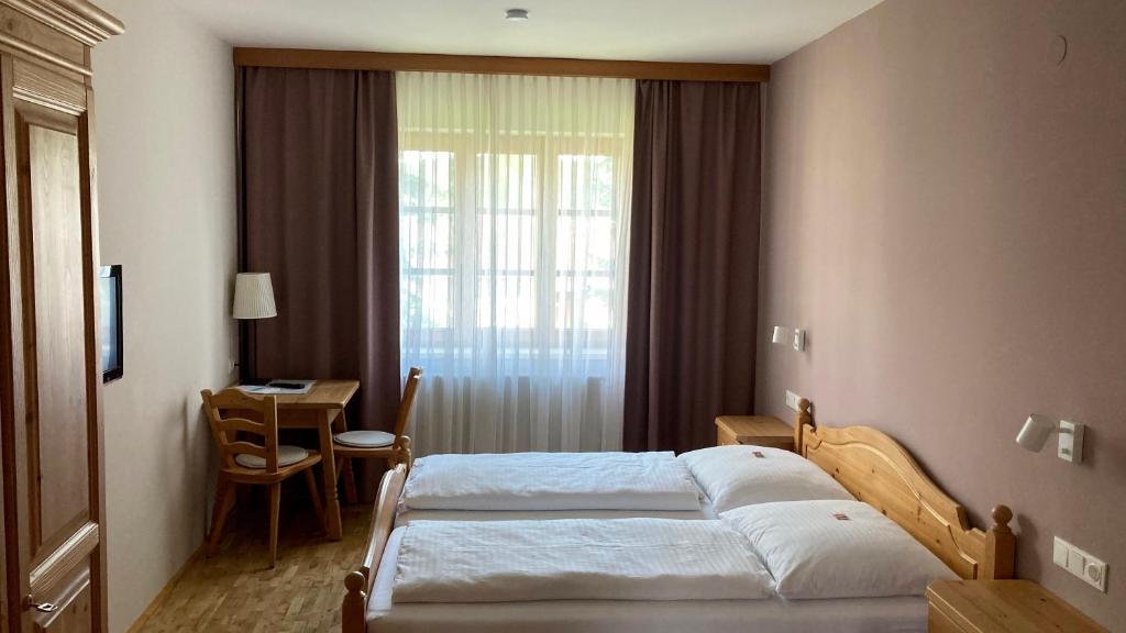 KapellnZöchbauer Gästehaus - Hotel Garni的一间卧室设有两张床、一张桌子和一个窗口。